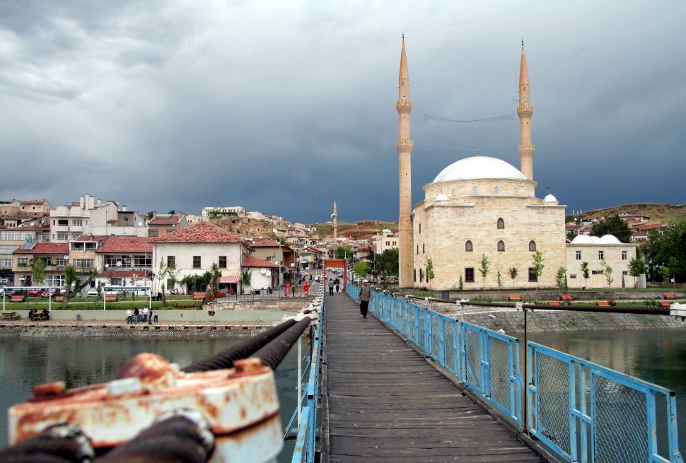 a bridge with a body of water and a building in the background