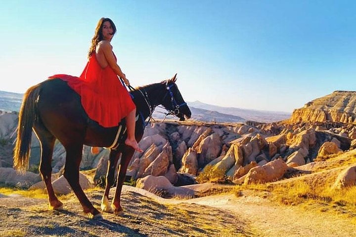 a woman in a red dress riding a horse